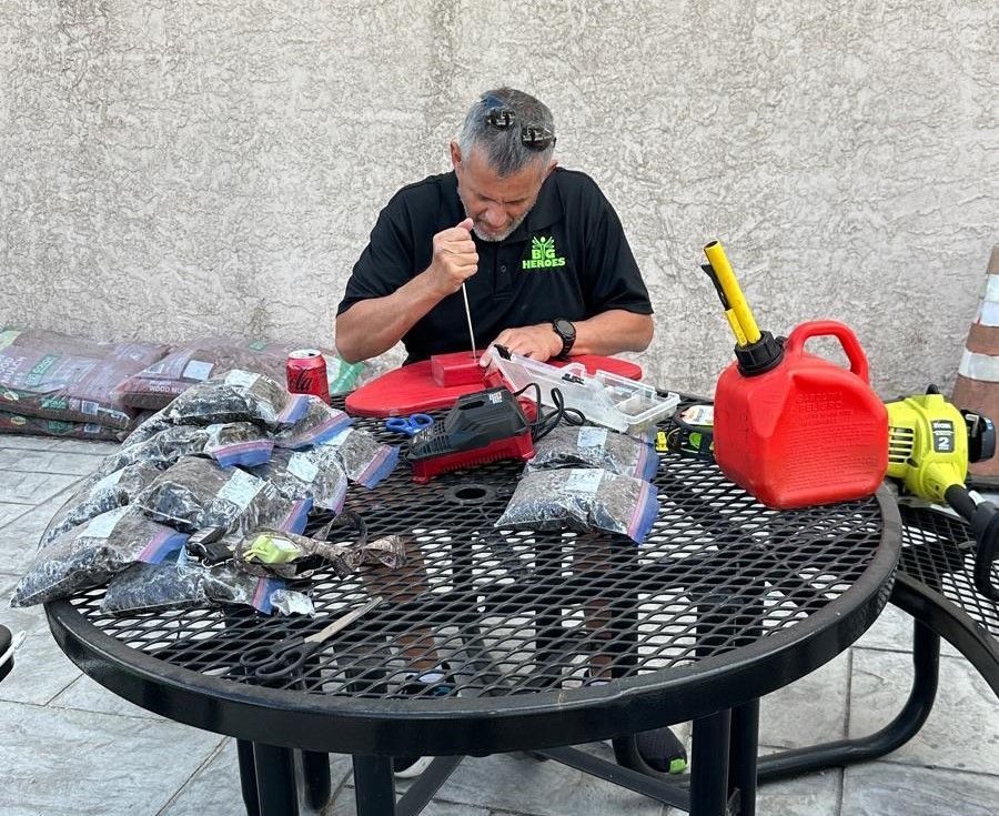A man is sitting at a table with tools and a gas can.