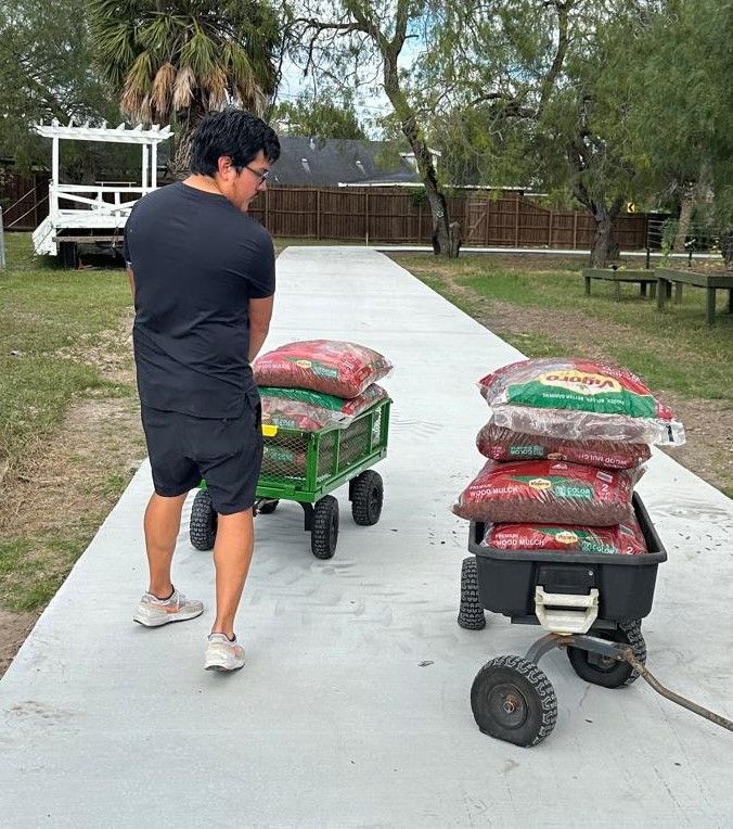 A man is pushing a cart with bags of dirt on it.