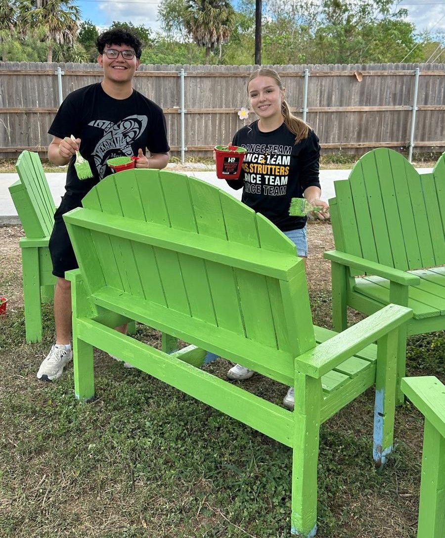 A man and a woman are standing next to a green bench.