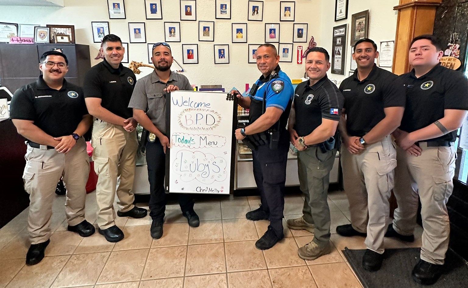 A group of police officers are standing next to each other holding a sign.