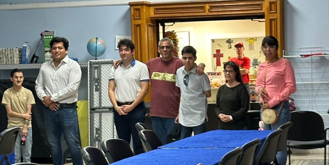 A group of people standing around a table with a blue table cloth