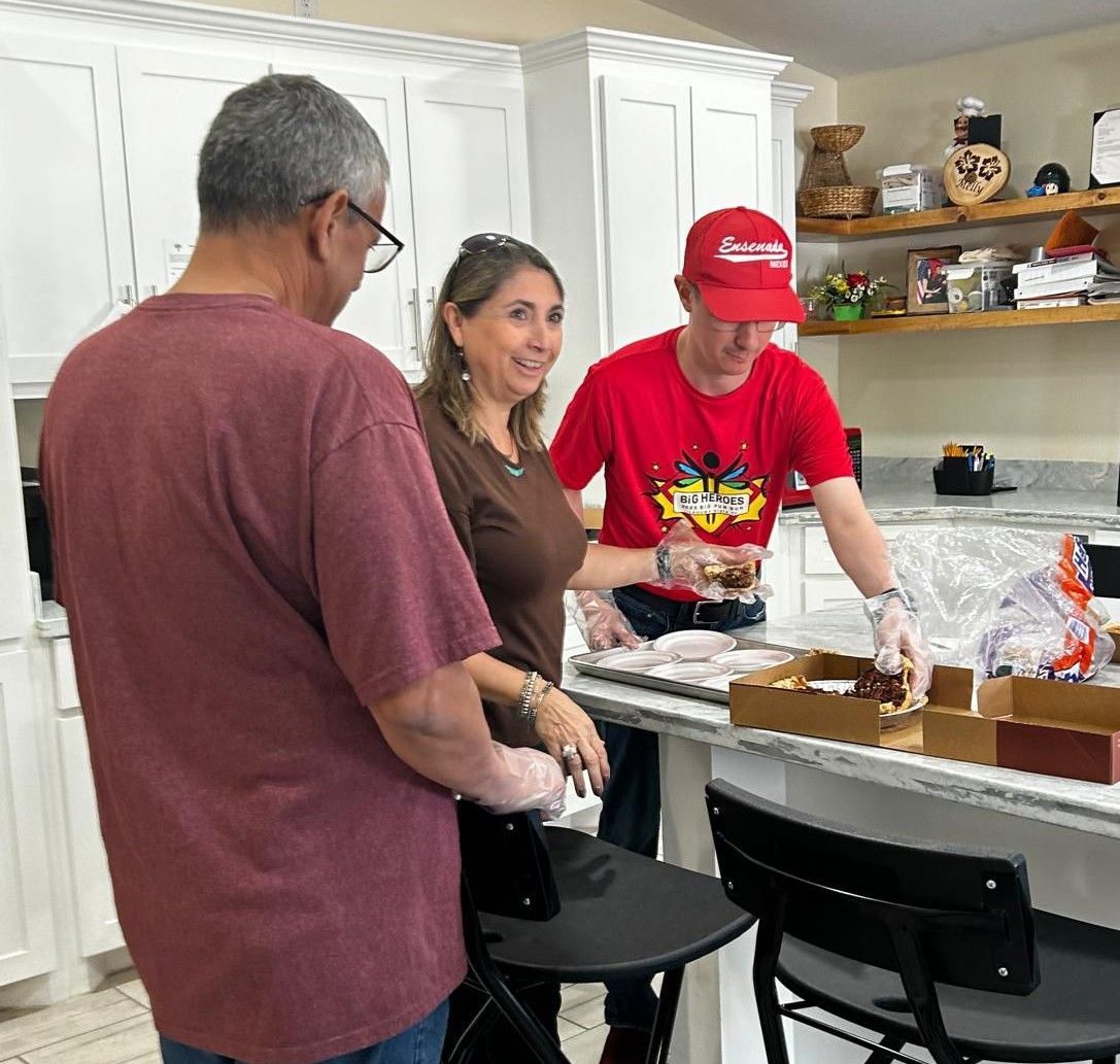 A man in a red shirt is standing next to a woman in a kitchen.