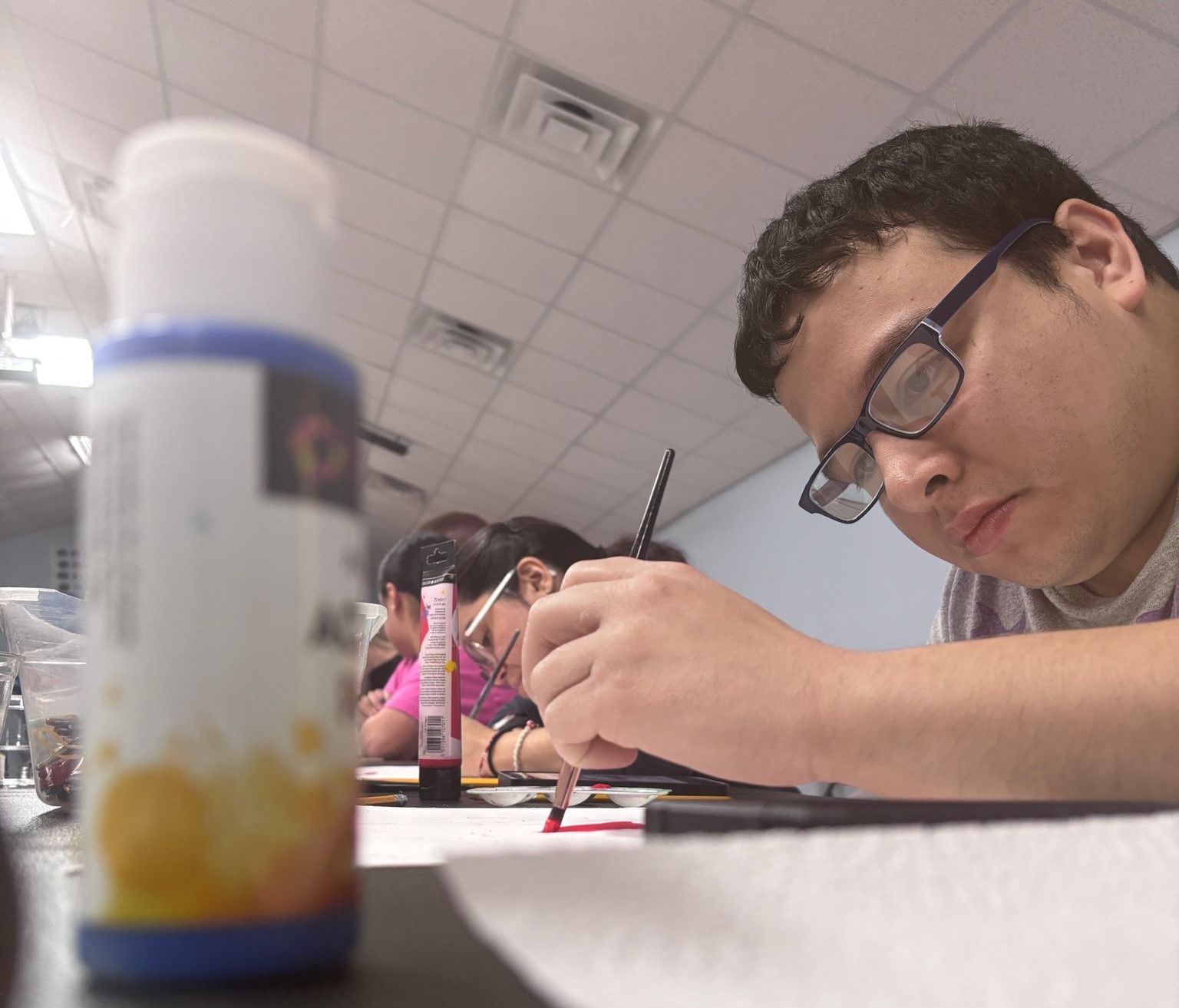A man wearing glasses is writing on a piece of paper