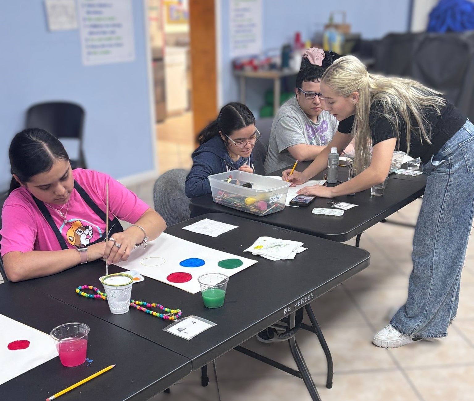 A group of people are sitting at a table painting