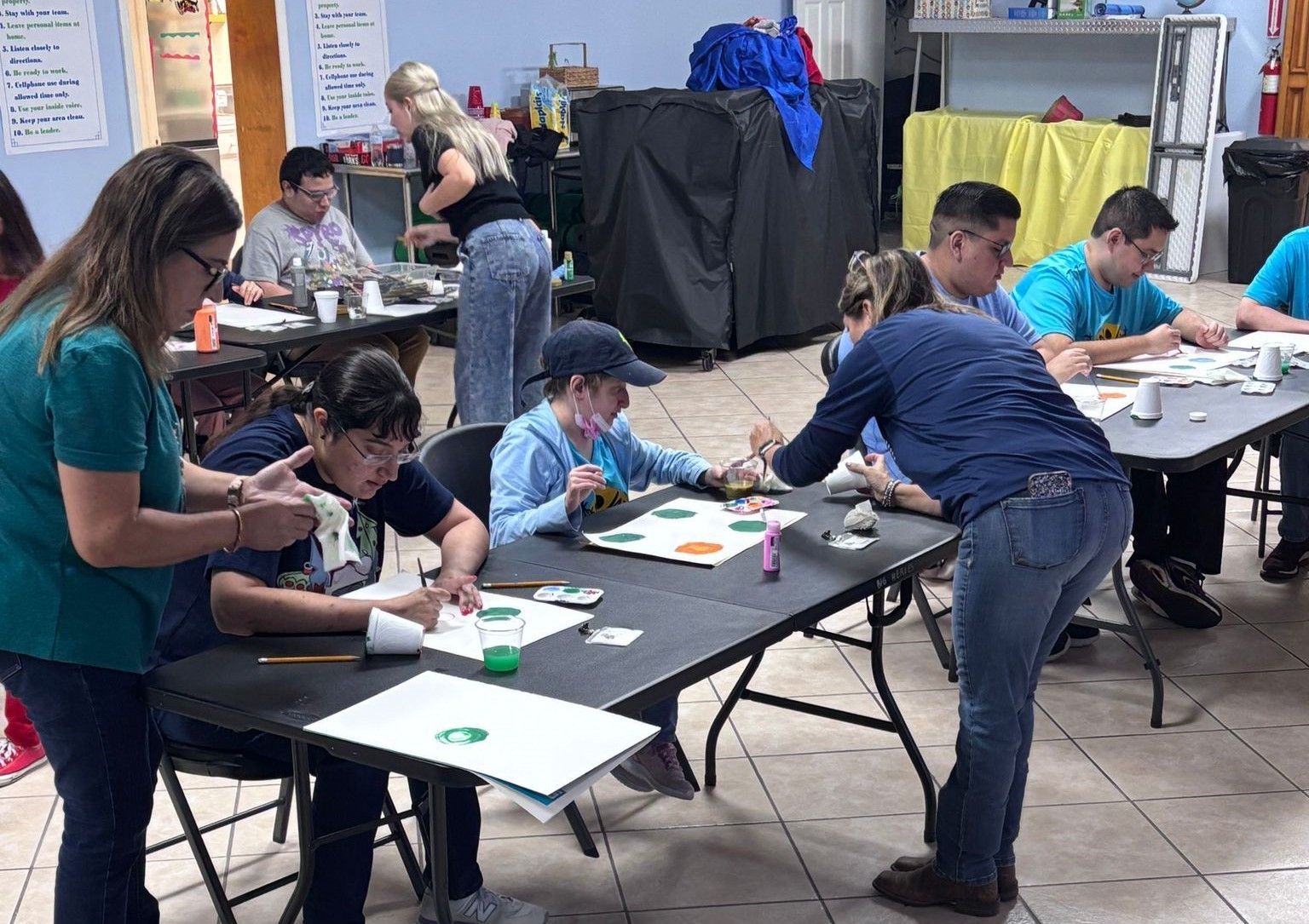 A group of people are sitting at tables painting.