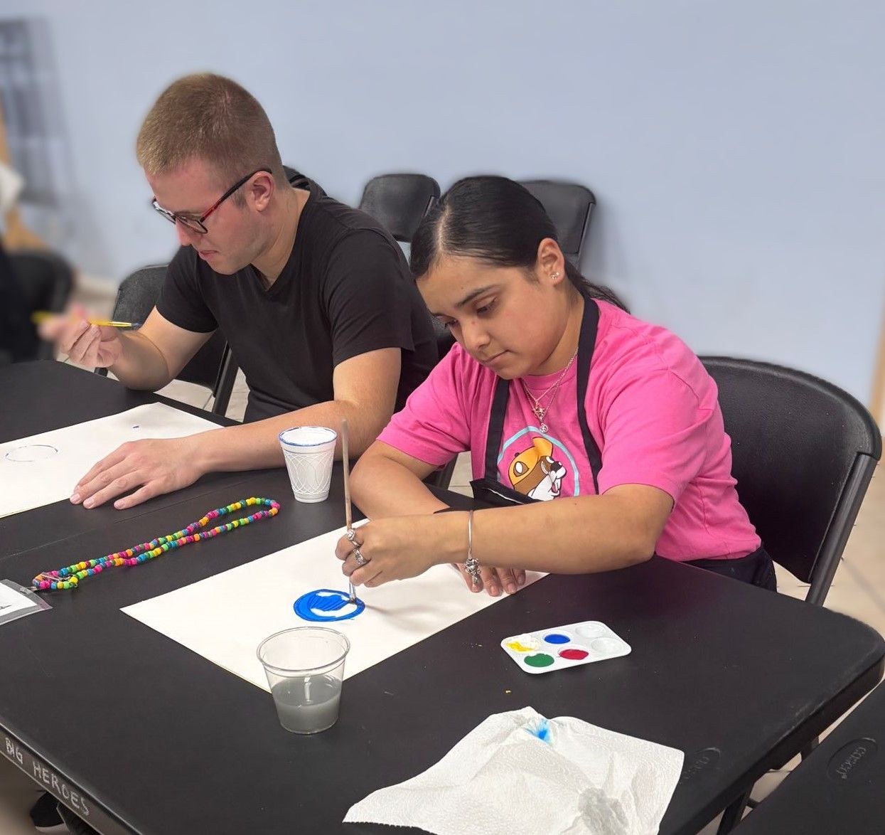 A man and a woman are sitting at a table painting