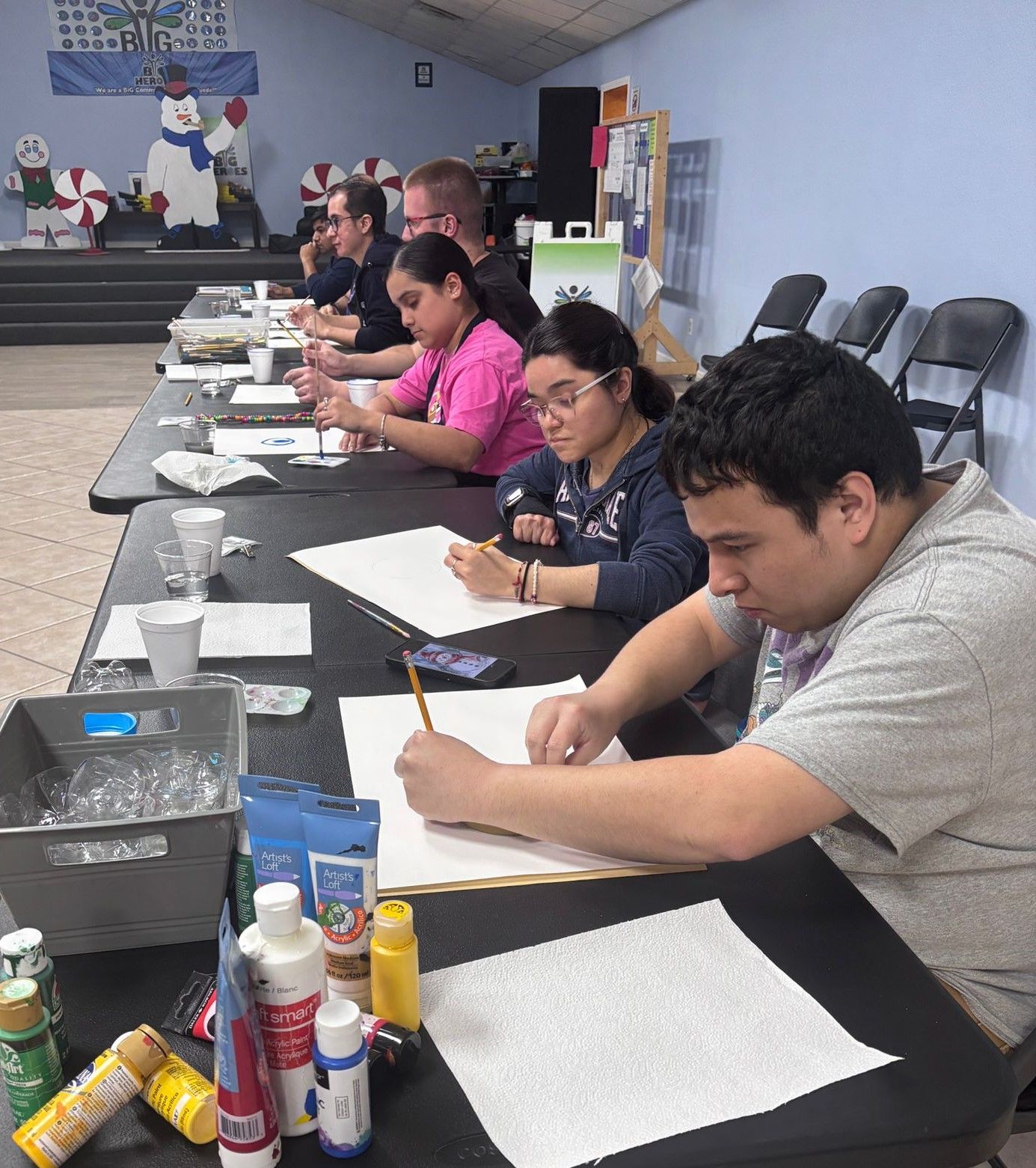 A group of people are sitting at tables writing on paper
