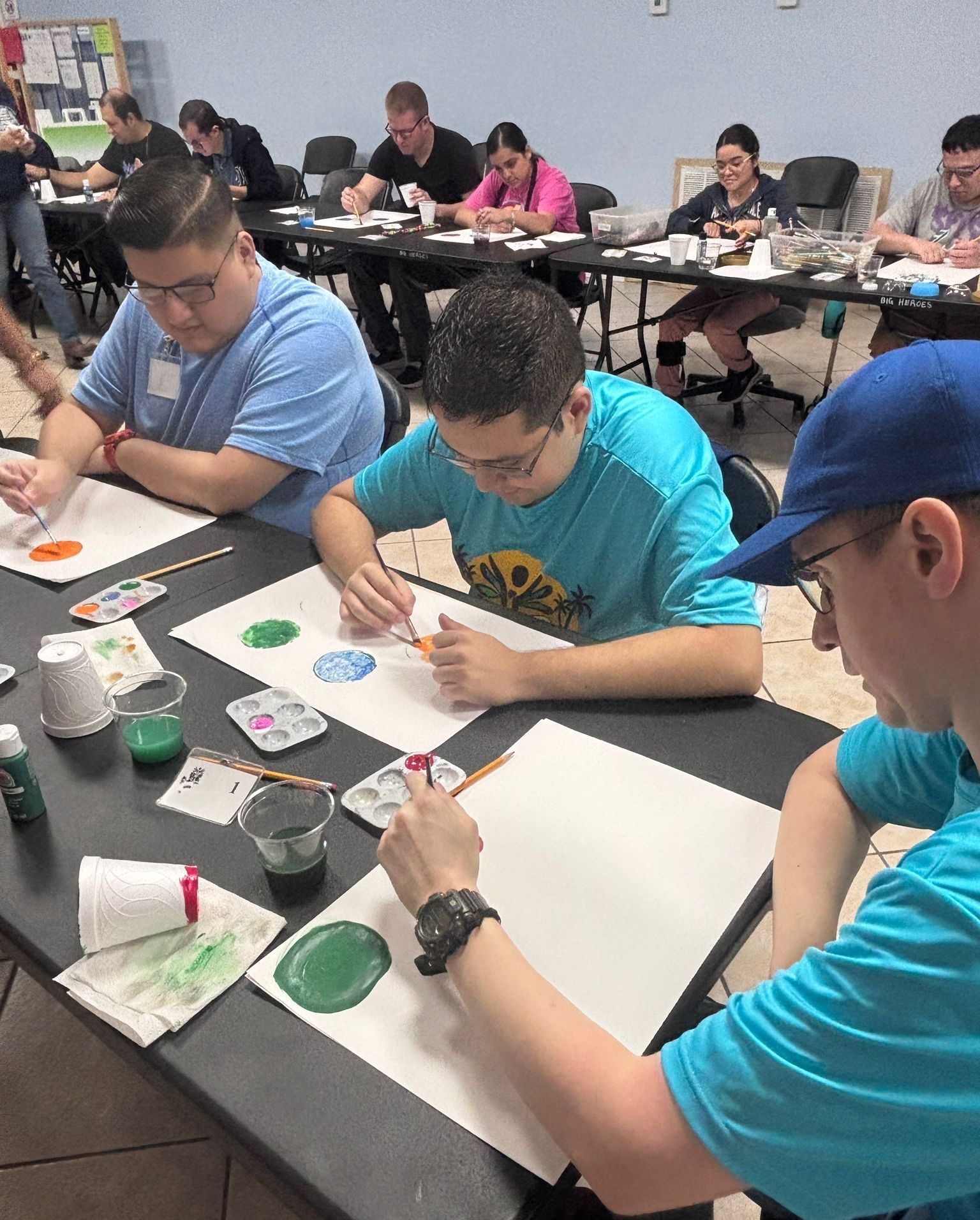 A group of people are sitting around a table painting