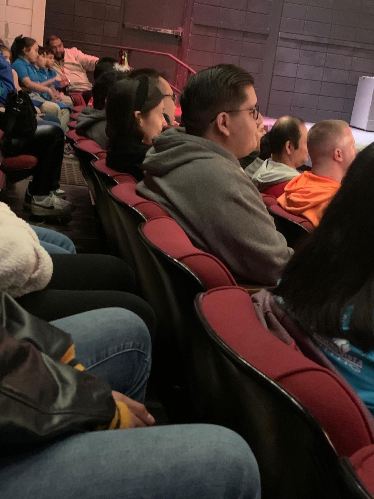 A group of people are sitting in a theater watching a play