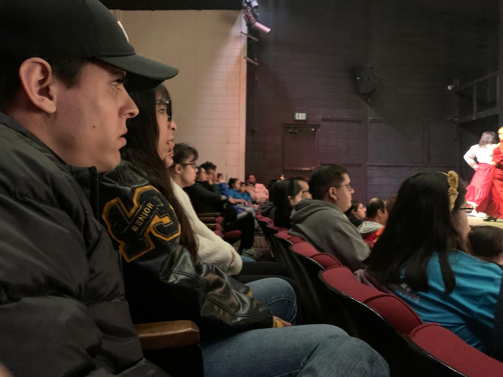 A group of people are sitting in a theater watching a play