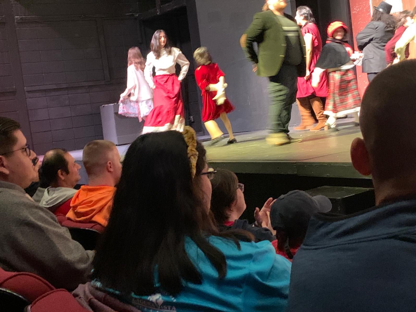 A group of people sitting in a theater watching a play