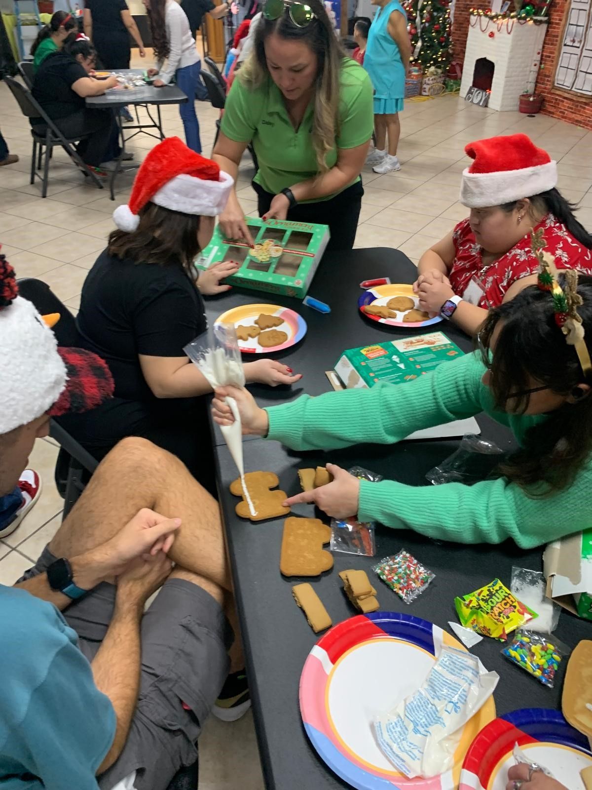 A group of people are sitting at a table decorating gingerbread cookies.