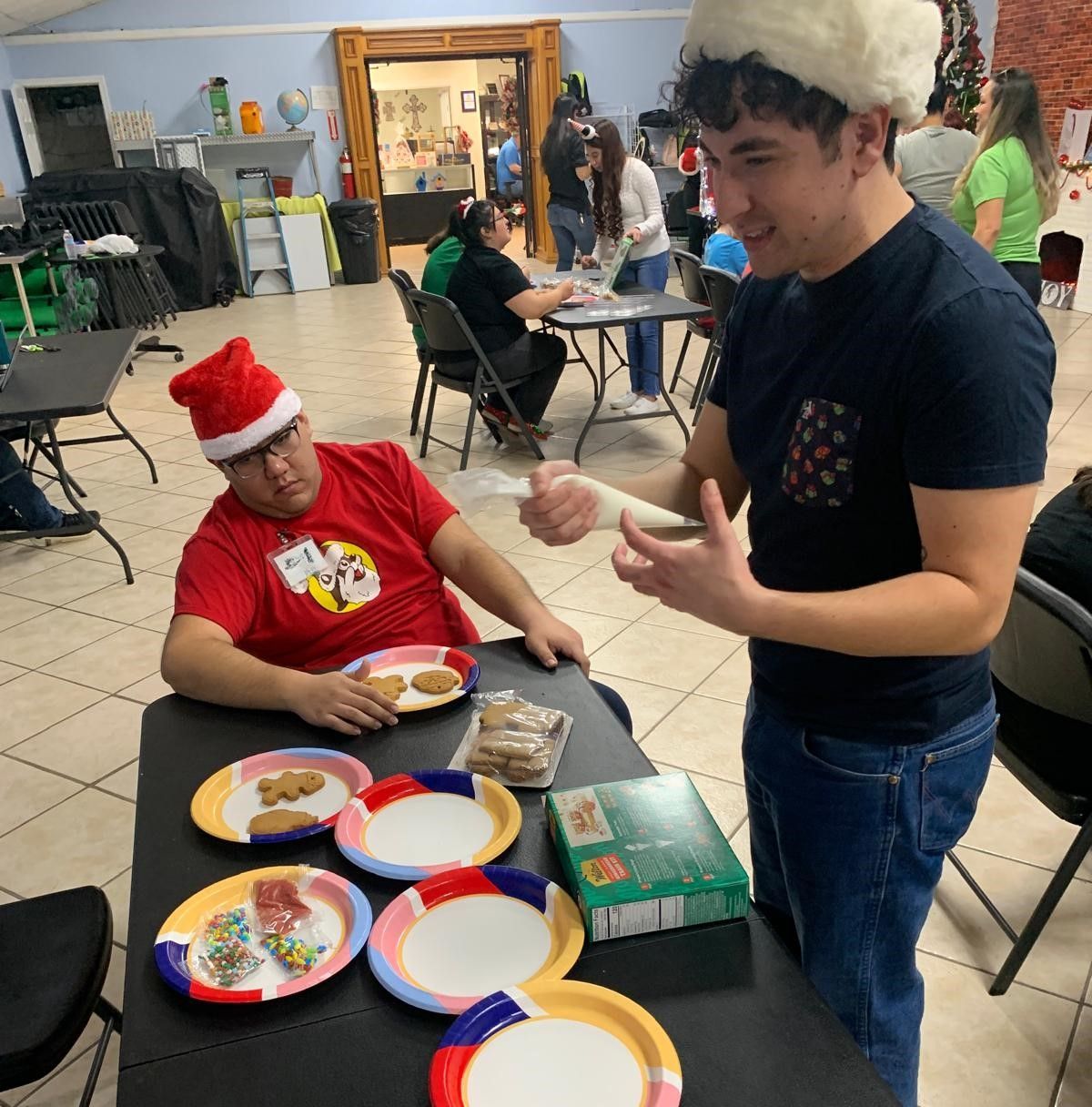 A man wearing a santa hat sits at a table with plates of food