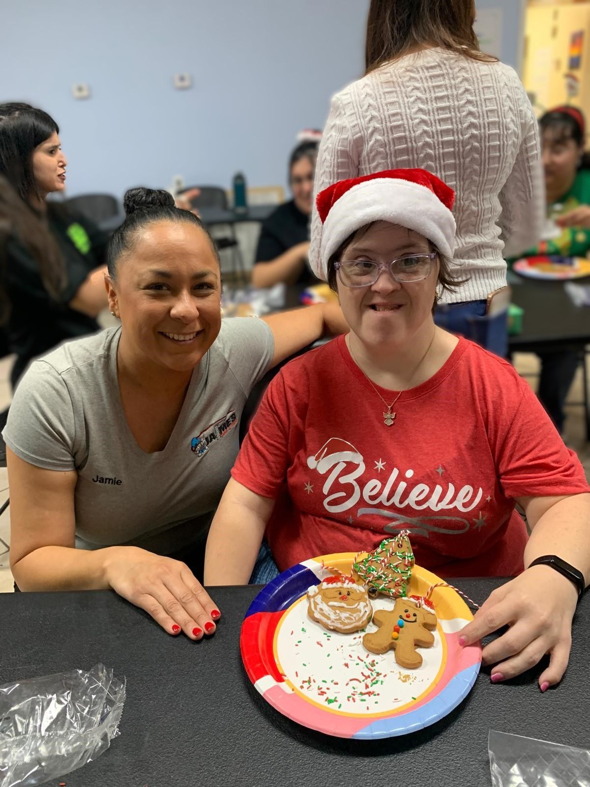 Two women are sitting at a table with a plate of gingerbread cookies.