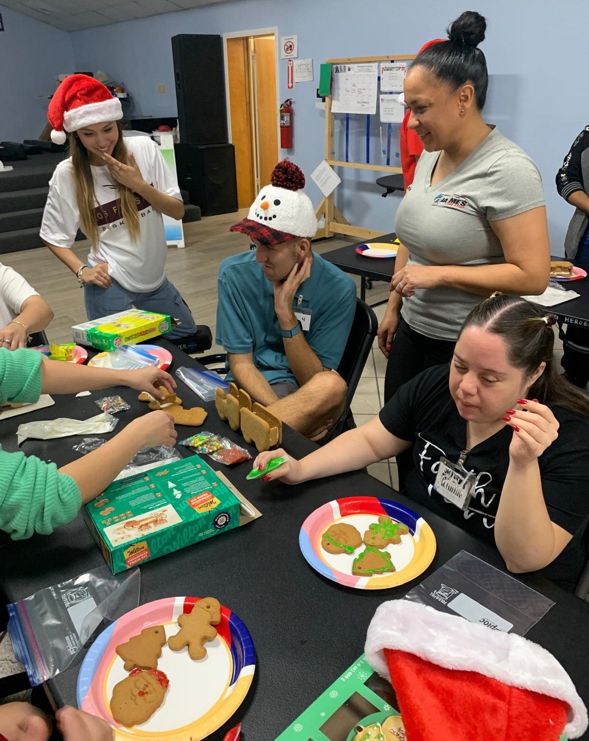 A group of people are sitting around a table eating gingerbread cookies.