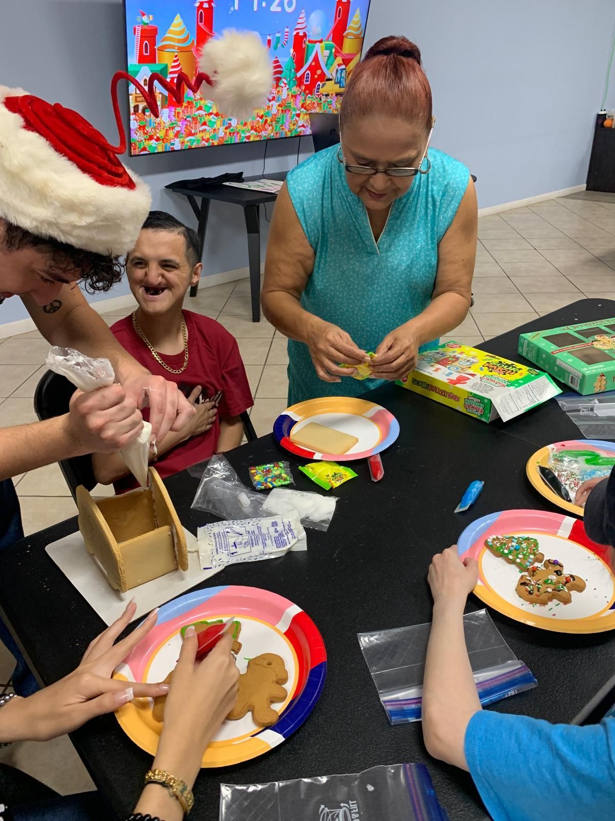 A group of people are sitting around a table decorating gingerbread cookies.