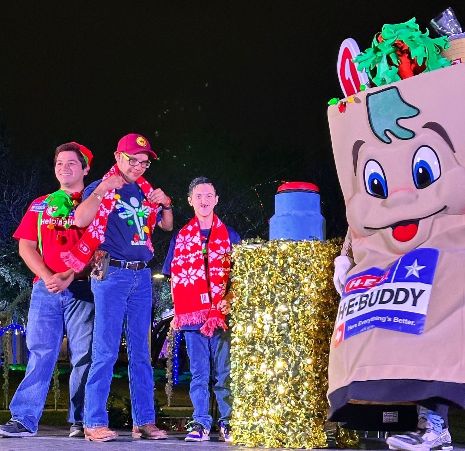A group of people standing next to a mascot that says the buddy