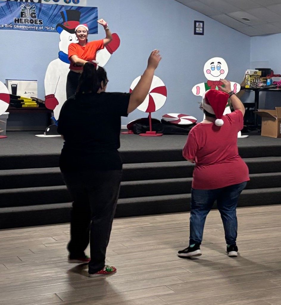 A group of people are dancing in a room with a snowman on the wall