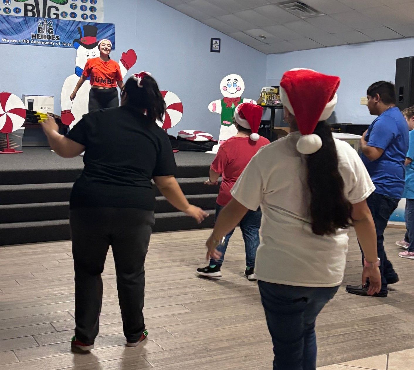 A group of people are standing in a room wearing santa hats