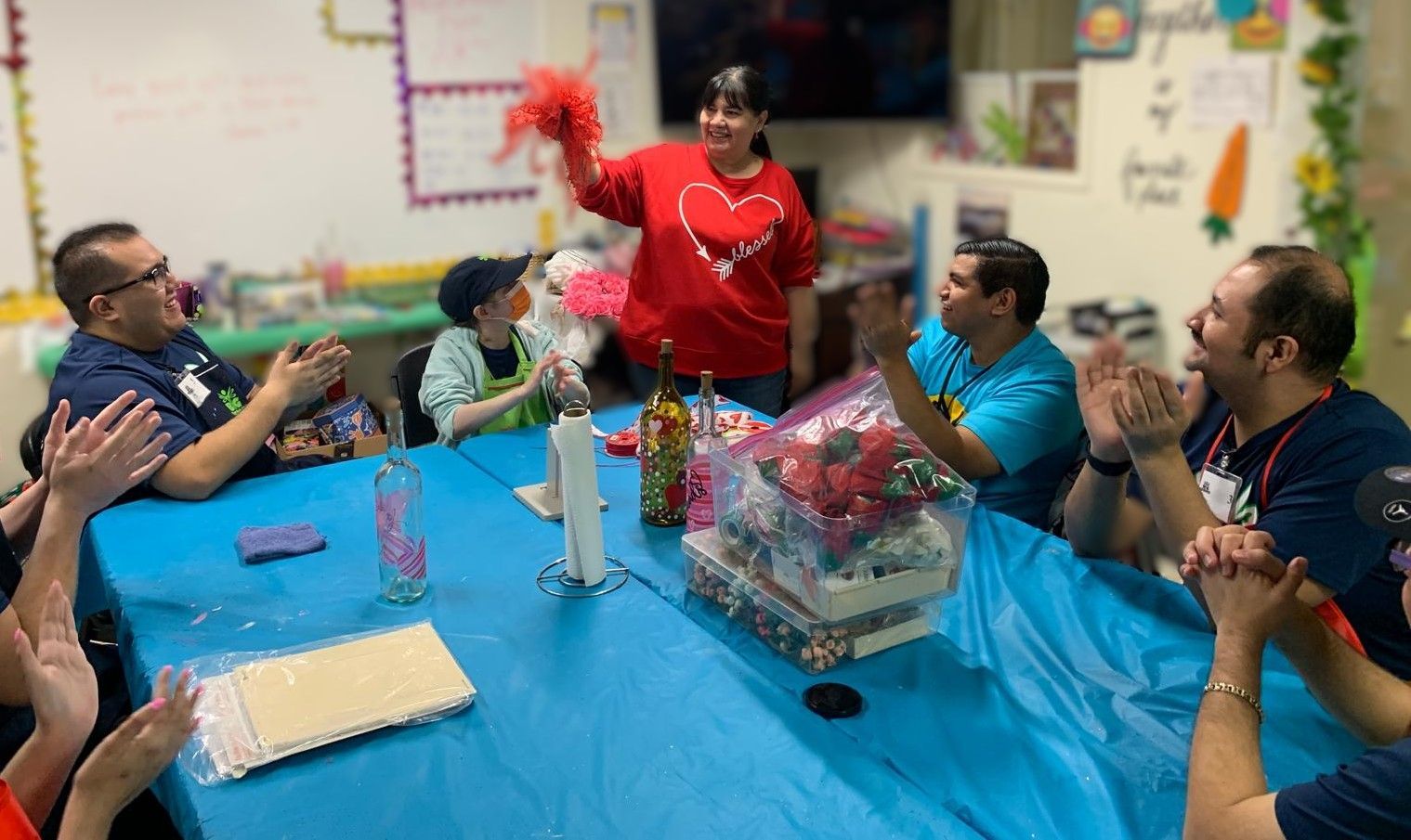 A group of people are sitting around a table applauding.