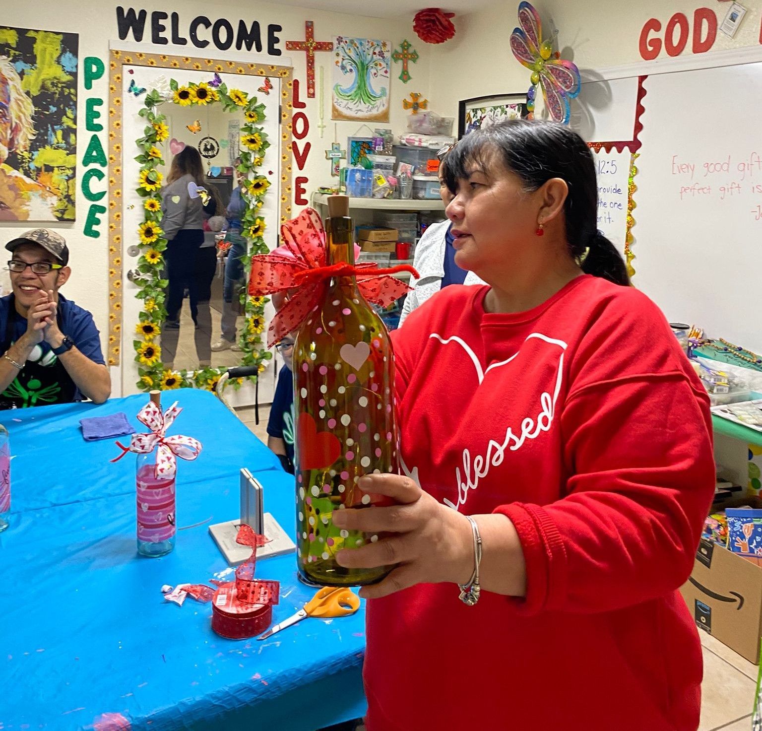 A woman in a red shirt that says blessed is holding a bottle