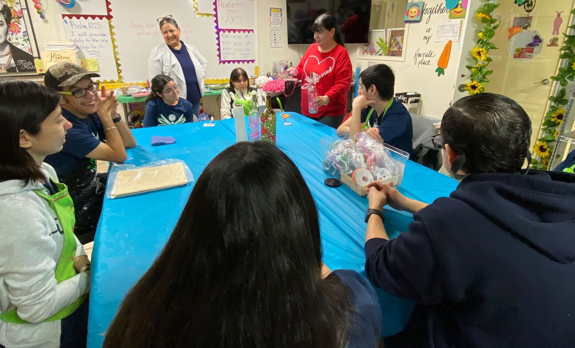 A group of people are sitting around a table in a classroom.
