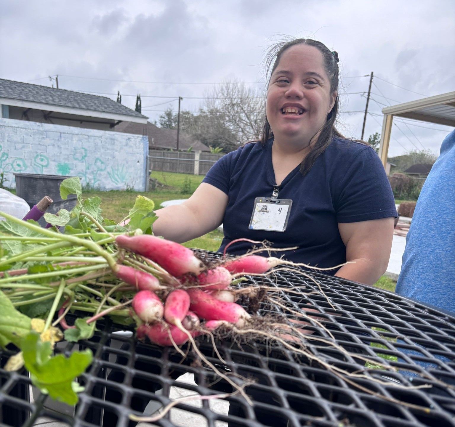 A woman is smiling while holding a bunch of radishes