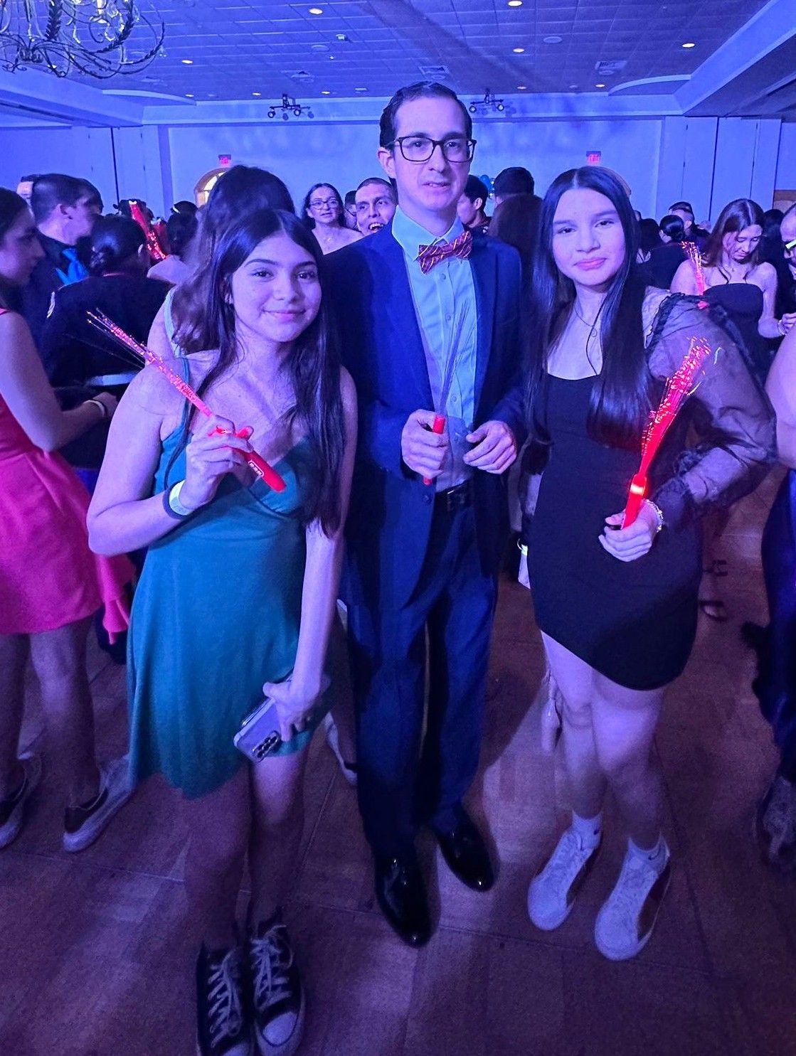 A man and two girls are posing for a picture at a party.
