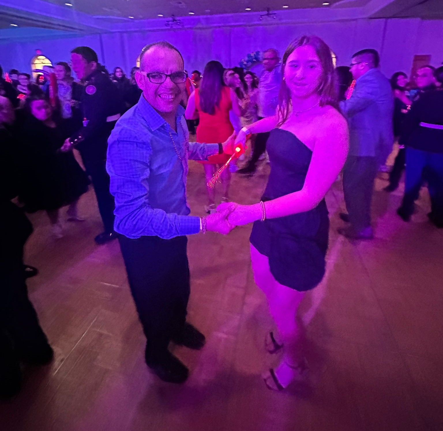 A man and a woman are dancing in a room with purple lights.