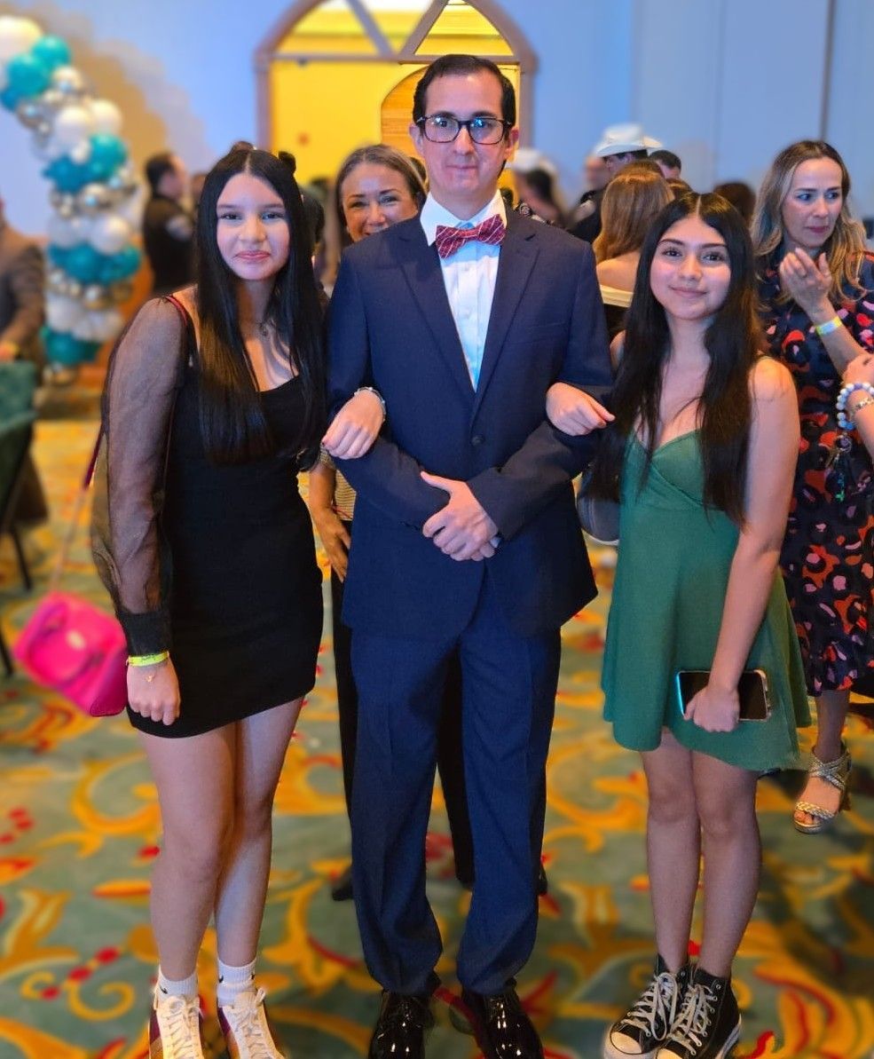 A man in a suit and bow tie poses with two women