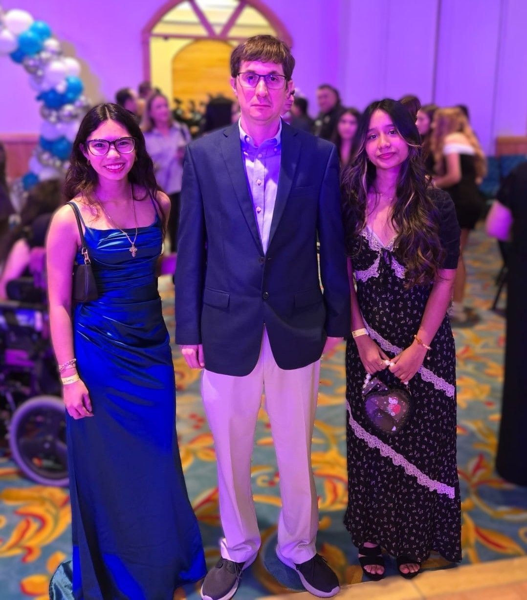 Three people posing for a picture in a room with purple lights