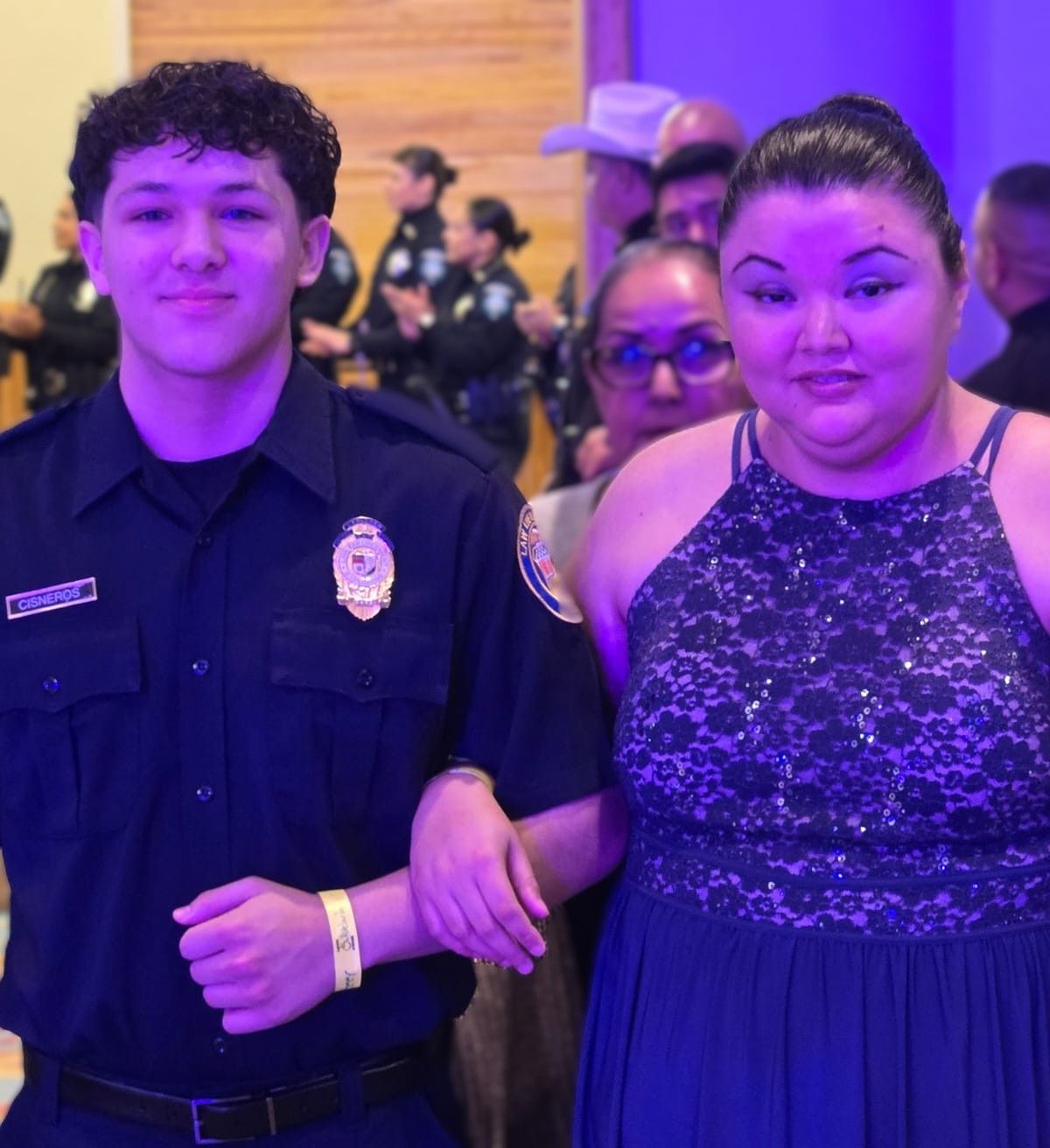 A man in a police uniform stands next to a woman in a lace dress
