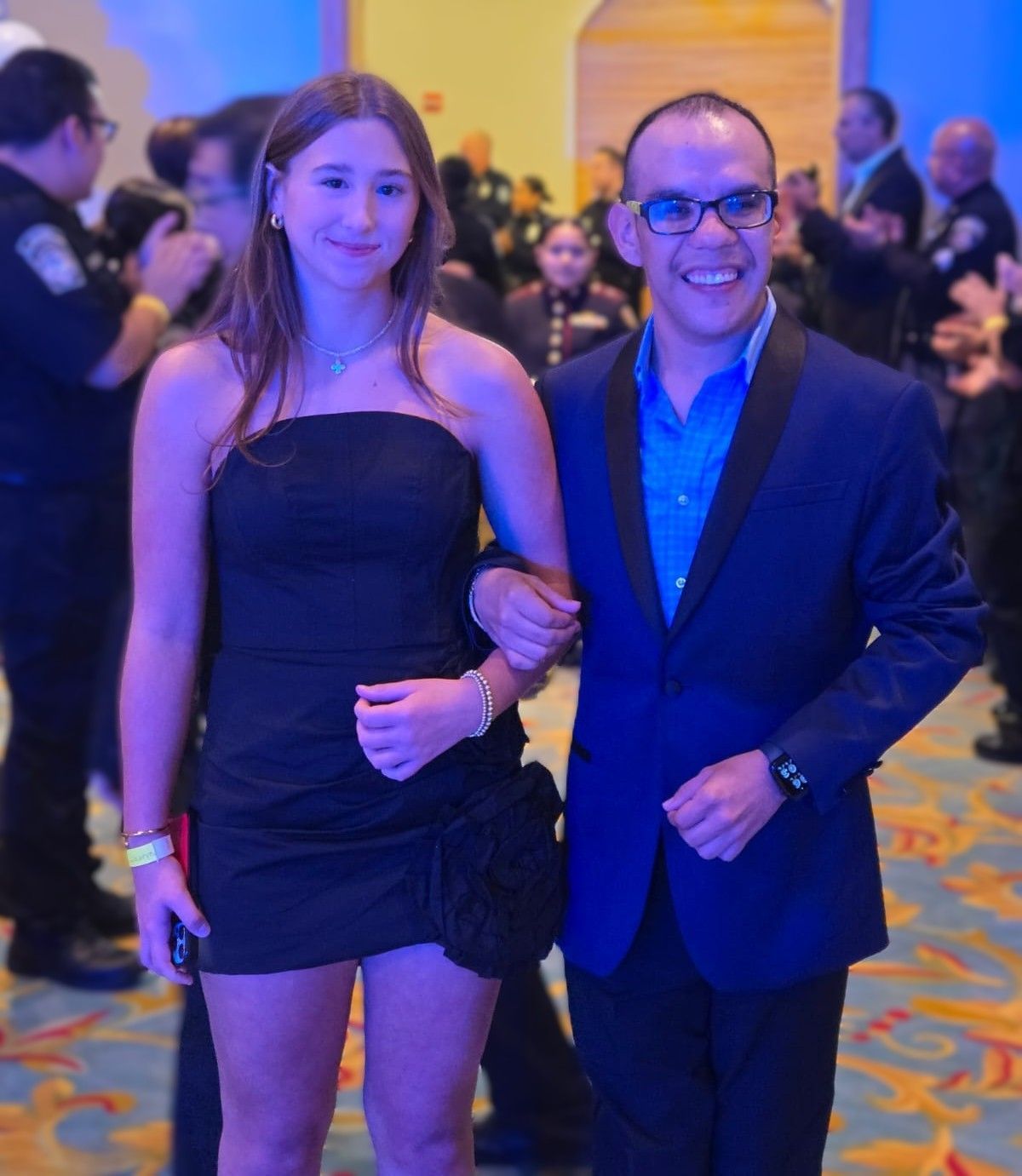 A man in a blue suit and a woman in a black dress pose for a picture