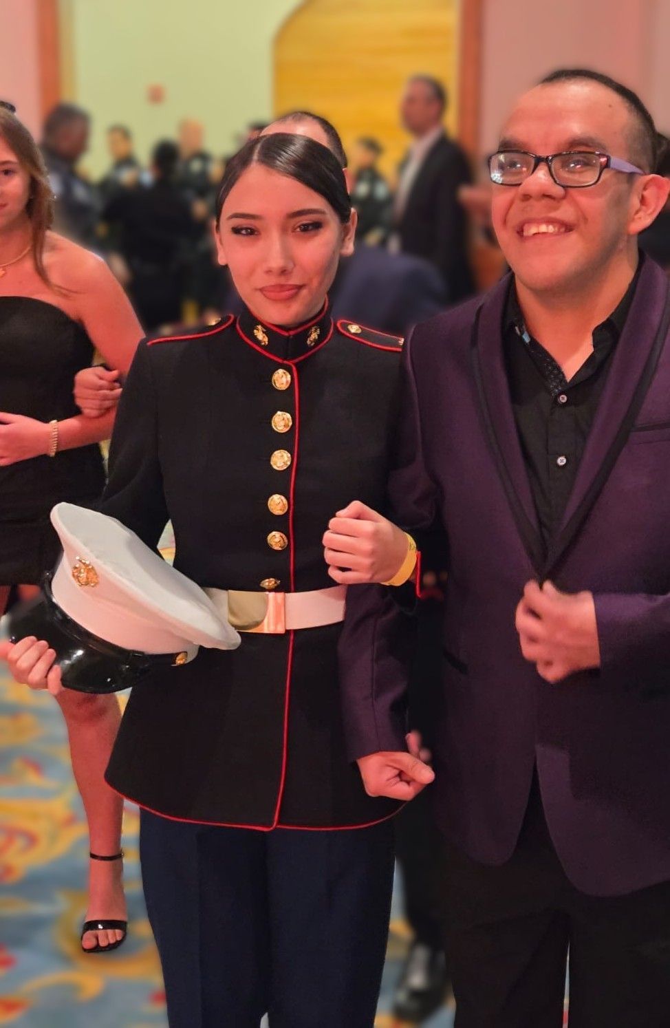 A man in a purple jacket stands next to a woman in a marine uniform