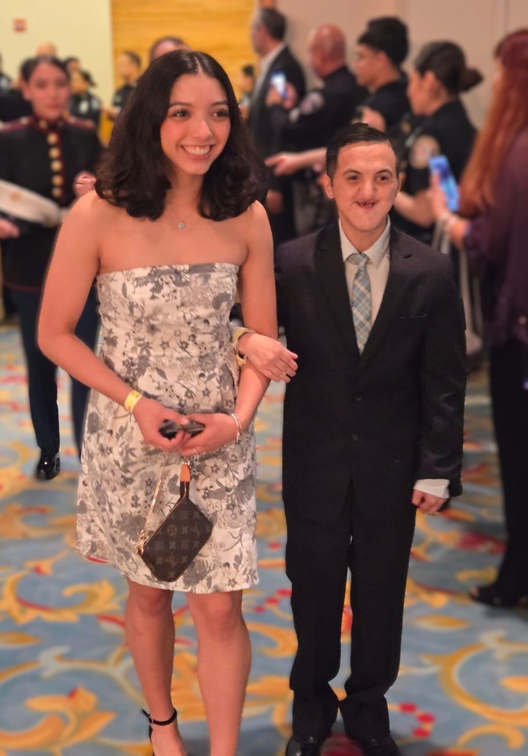 A woman in a strapless dress is walking next to a boy in a suit