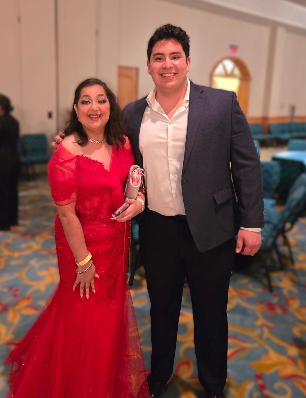A man in a suit and a woman in a red dress pose for a picture
