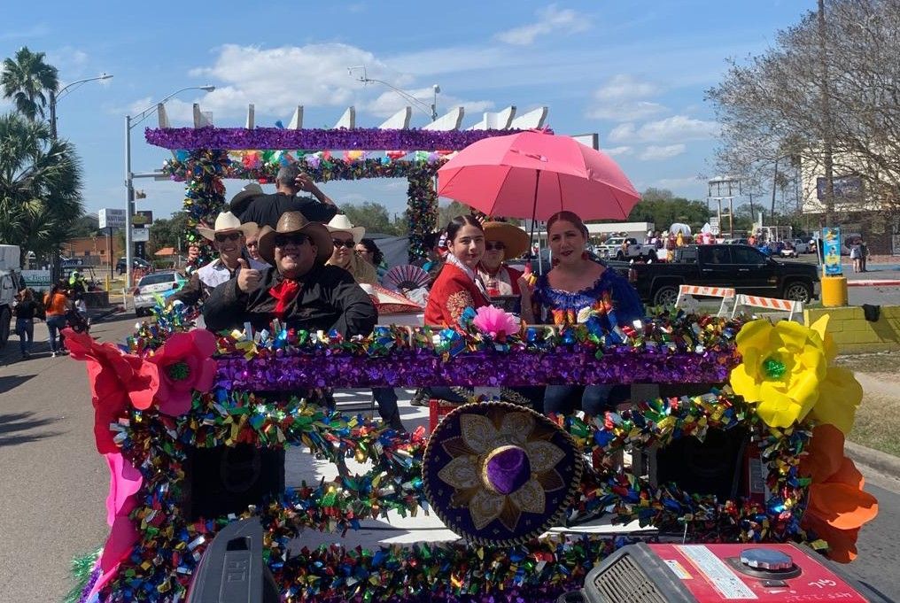 A group of people are riding in a car decorated with flowers and umbrellas.