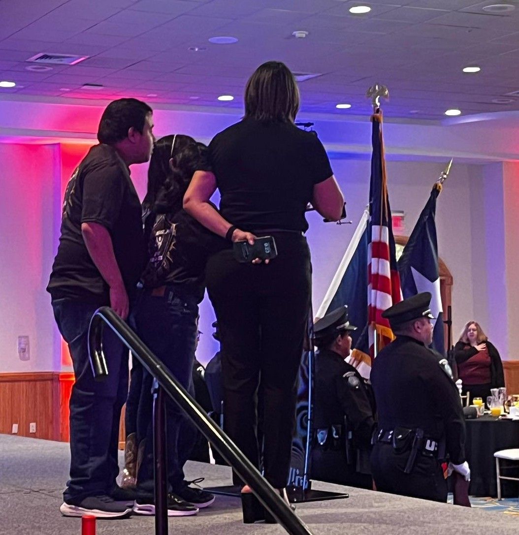 A group of people standing on a stage with flags in the background
