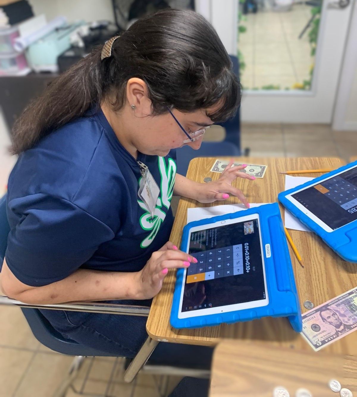 A woman is sitting at a desk using a tablet