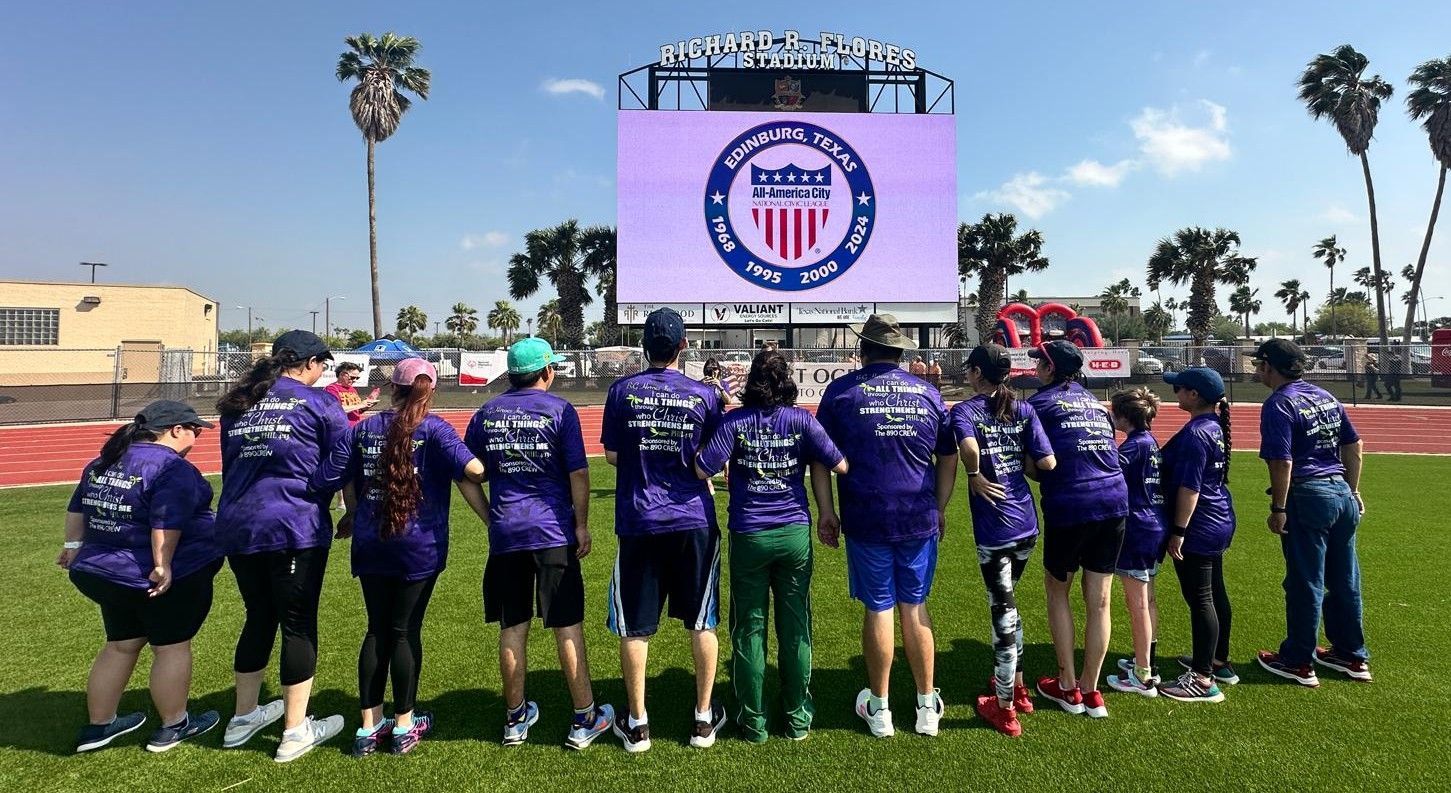 A group of people are standing in front of a large screen.