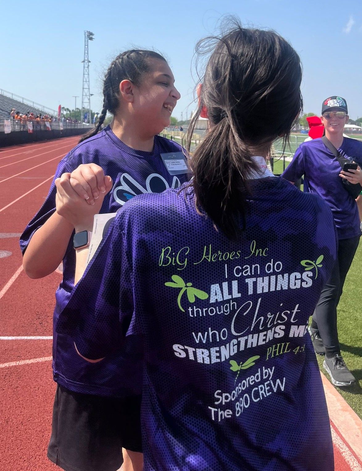 Two girls wearing purple shirts that say big heroes inc i can do all things through christ who strengthens me