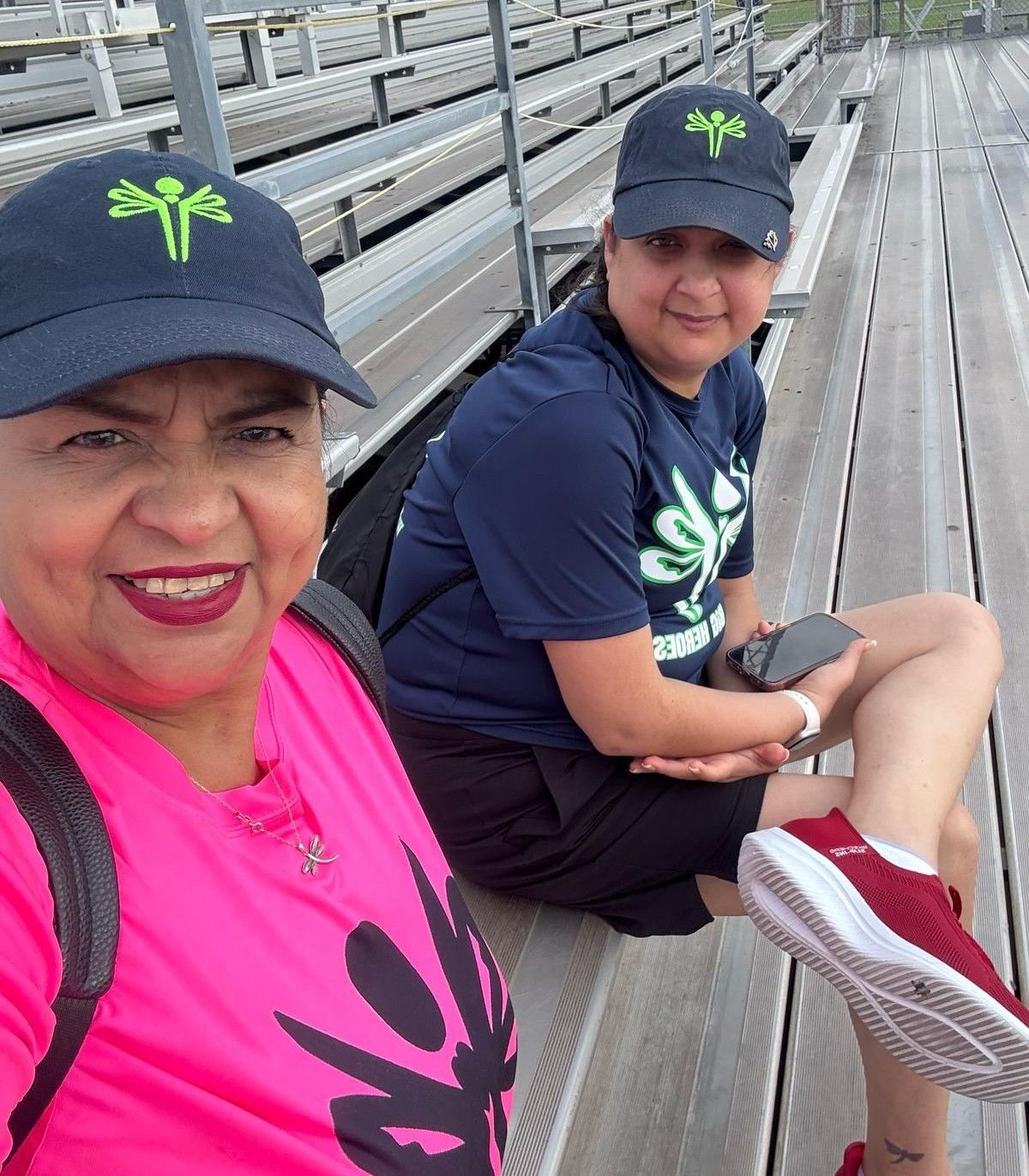 A woman in a pink shirt is sitting next to another woman in a blue shirt