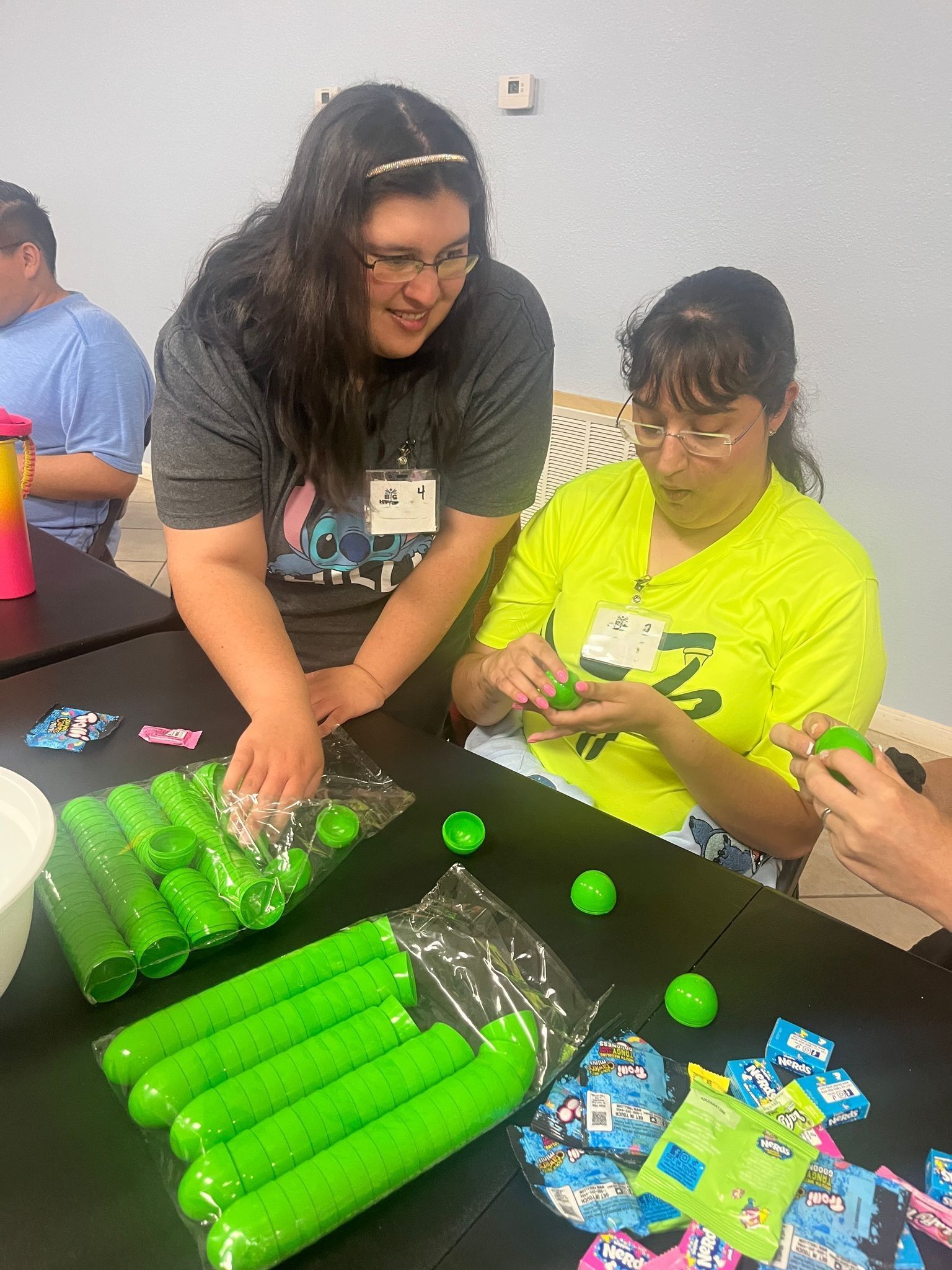 A group of people are sitting at a table playing with green balls.