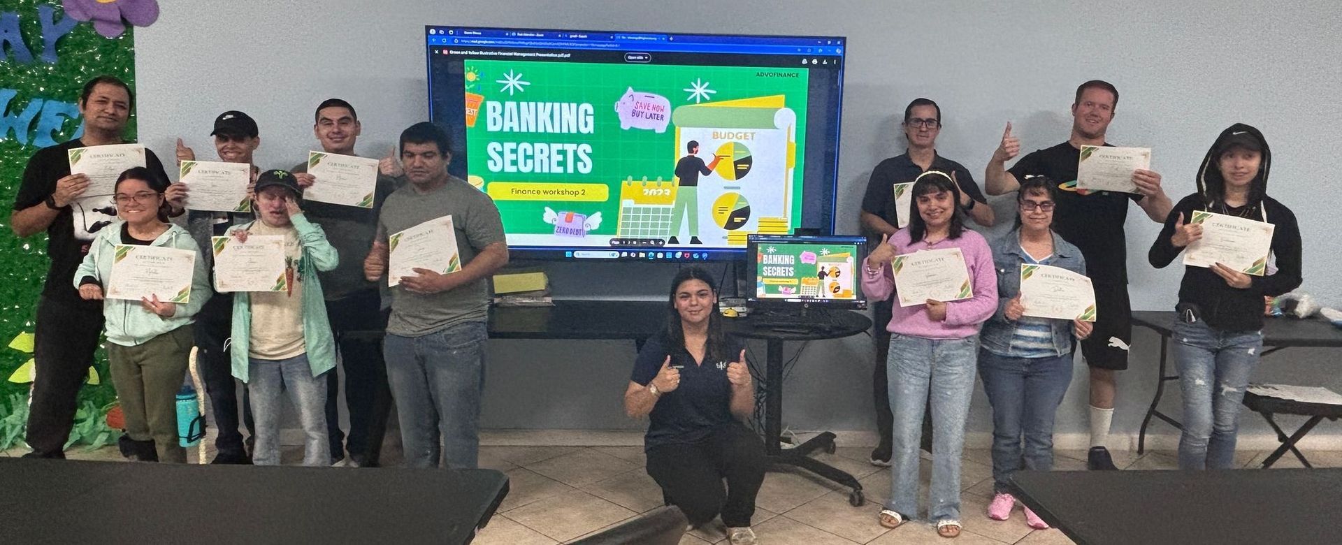 A group of people are standing in front of a large screen holding certificates.
