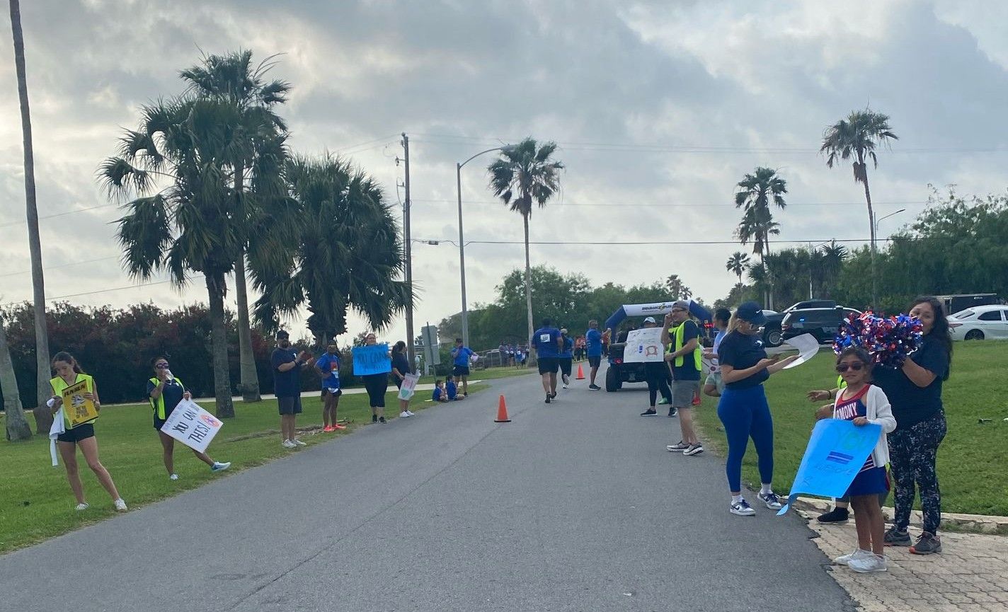 A group of people are standing on the side of a road holding signs.