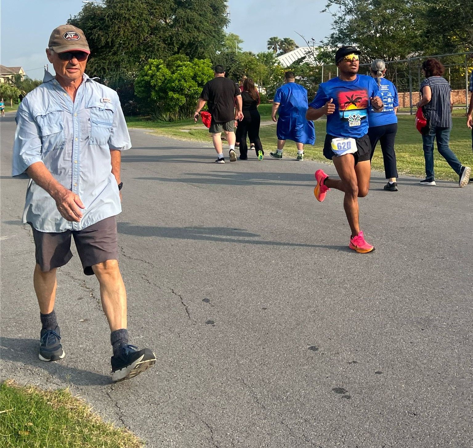 A group of people are walking down a street and one of them is wearing a shirt that says ' marathon ' on it