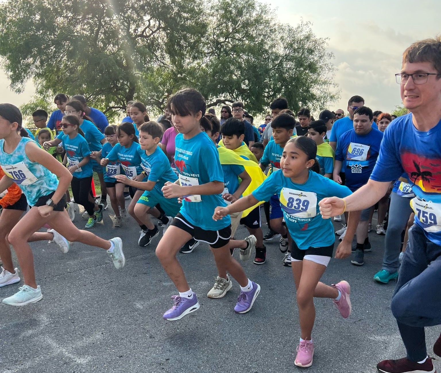 A group of children are running in a race with numbers on their shirts