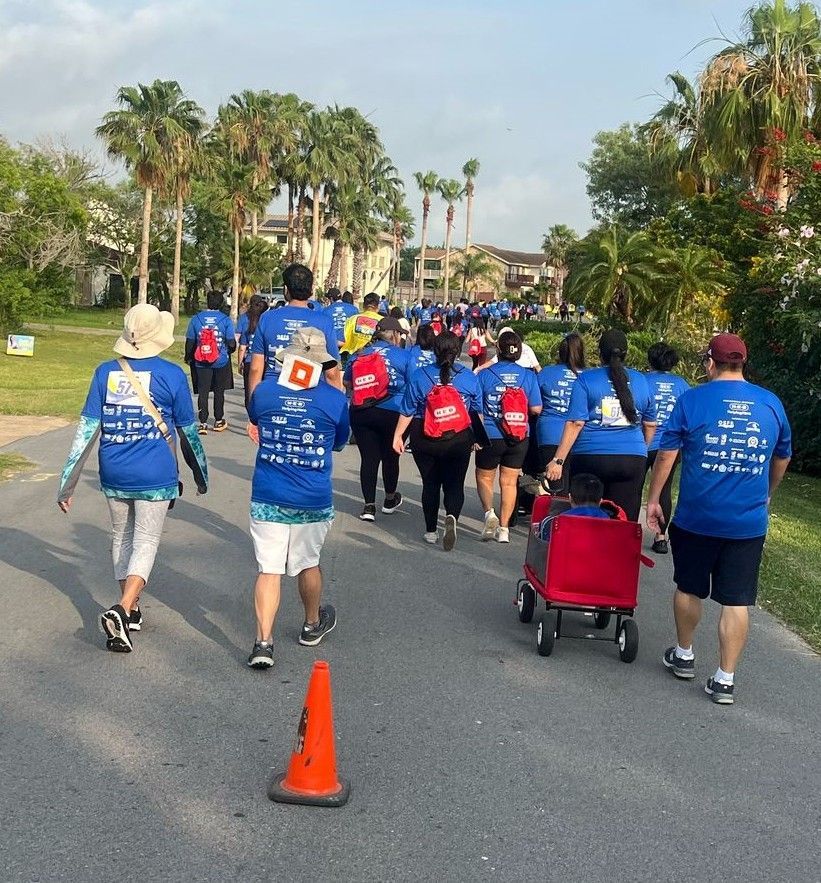 A group of people walking down a street wearing blue shirts