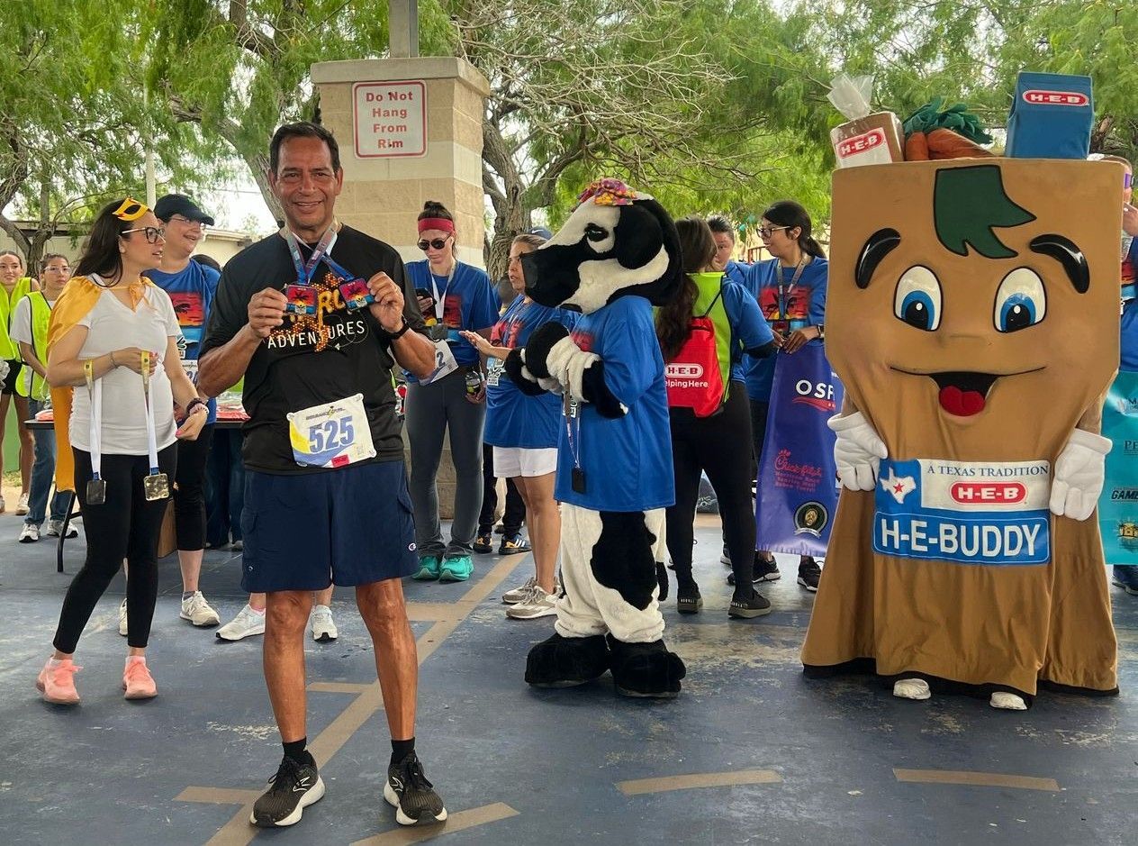A man is standing next to a mascot that says he e buddy