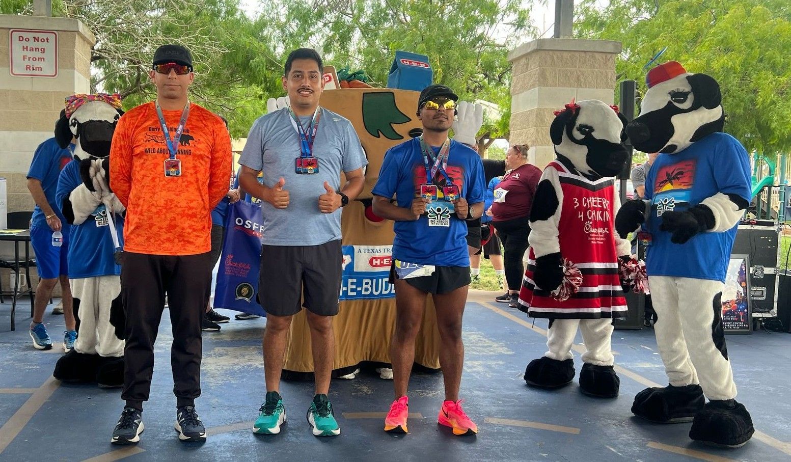 A group of people standing next to mascots in a parking lot.